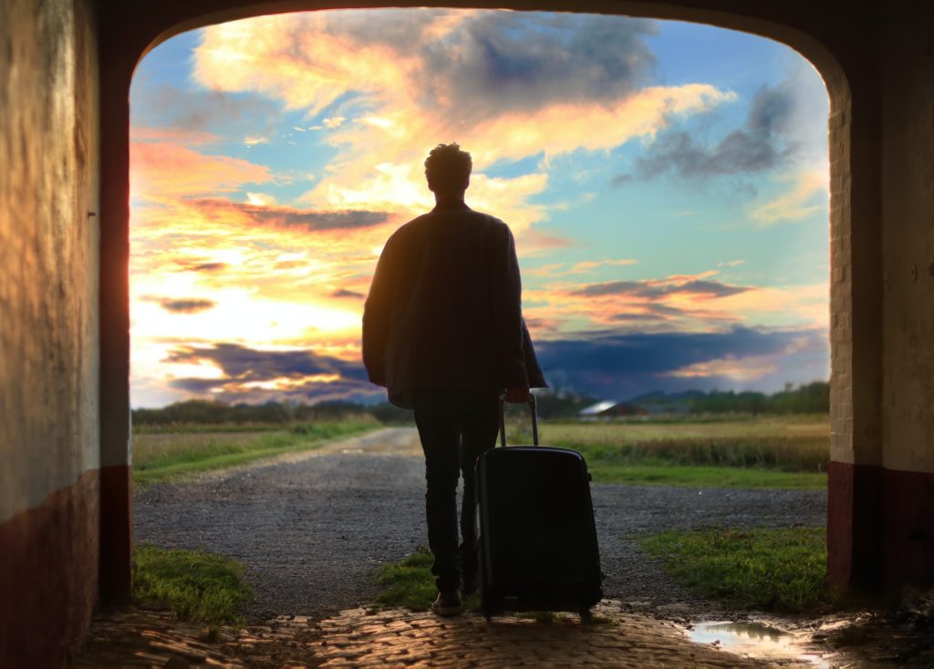 homme avec une valise avec fond couché de soleil